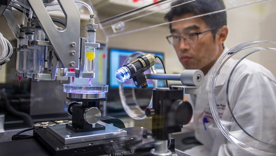 Researcher watching machine create tissue
