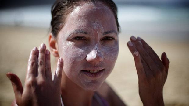 Woman putting sunscreen on her face.
