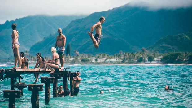 Man jumping off a pier into water.